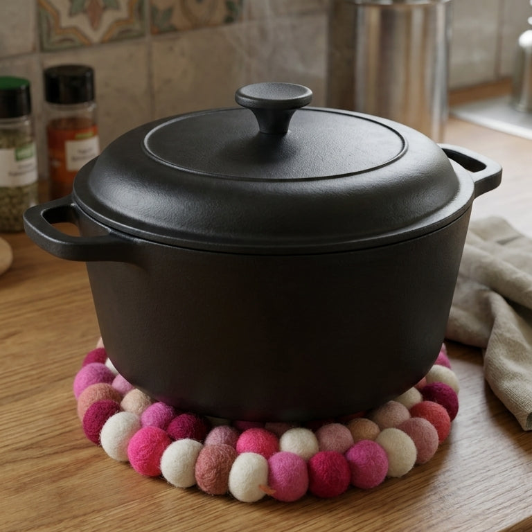 Black pot on a wooden surface with colorful pom-pom trivet