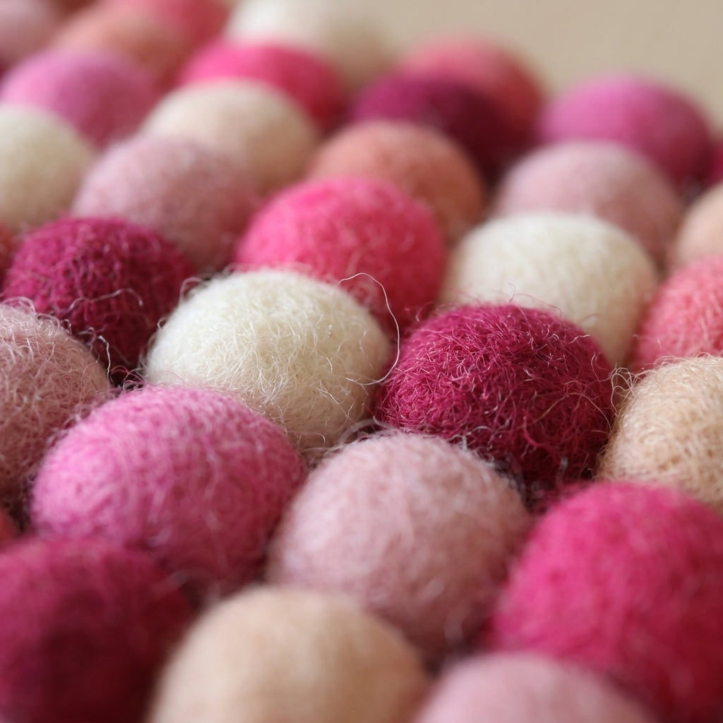 Close-up of pink and beige felt balls arranged in a pattern.