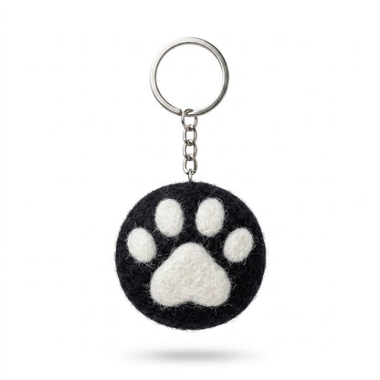 Black wool felt cat paw keyring with white paw print with a paw print design on a white background