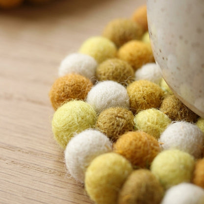 Mustard Yellow wool felt coasters handmade in Nepal, warm absorbent non-scratch drink coasters for wooden tables, teacher gifts, host gifts and new home buyers on a wooden surface