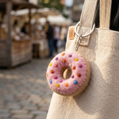 Felt Donut Keychain – Pink Sprinkle Wool Key Ring, Handmade in Nepal attached to a beige bag with a blurred market background
