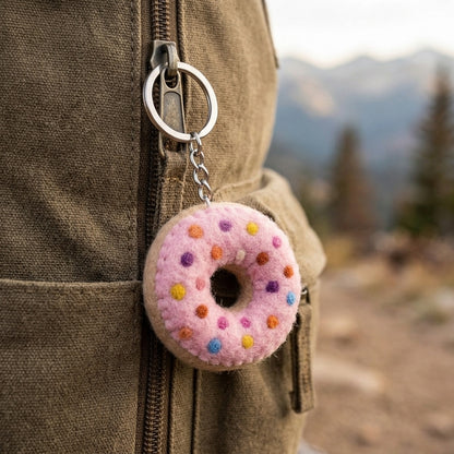 Felt Donut Keychain – Pink Sprinkle Wool Key Ring, Handmade in Nepal Felt attached to a backpack against a mountainous background