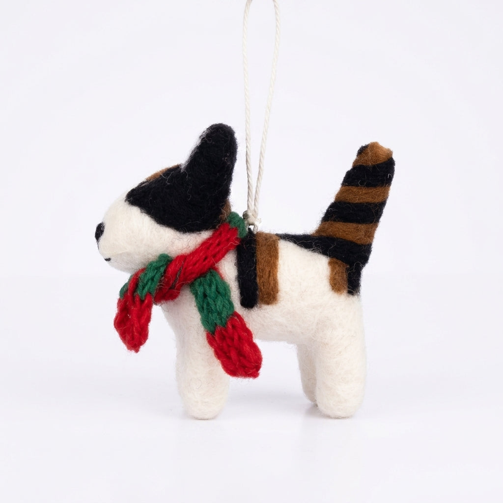 Handmade wool felt black and white cat ornament with hanging thread with a red and green scarf on a white background