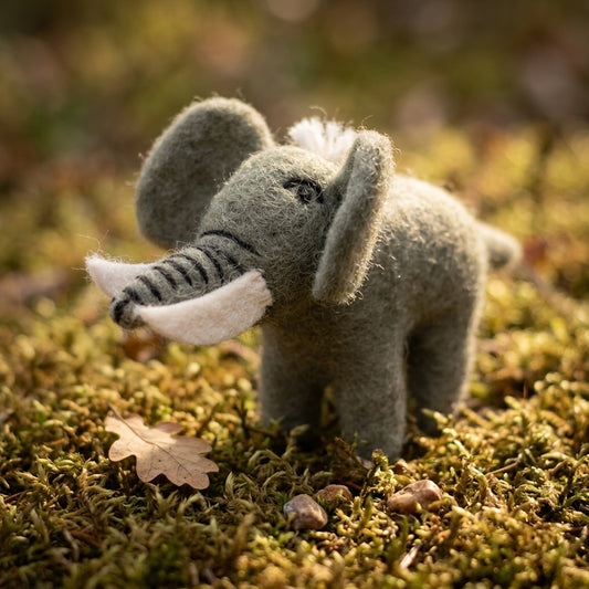 Handmade wool felt elephant ornament on a bed of moss with a blurred natural background