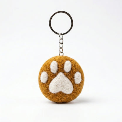 Orange wool felt cat paw keyring with white paw print on a white background
