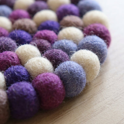 Plum Violet Purple wool felt coasters handmade in Nepal, jewel tone absorbent non-scratch drink coasters for wooden tables, tea lover gifts, host gifts and new home buyers on a wooden surface