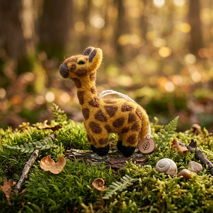 Wool felt giraffe ornament displayed on a mossy natural background
