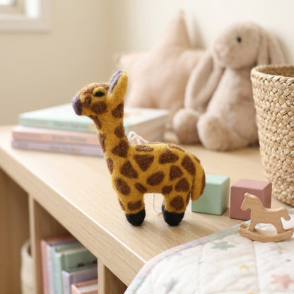 Handmade giraffe felt ornament styled on a nursery shelf
