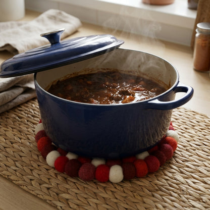 Blue cast iron pot with a lid on a red and white trivet, containing a stew.
