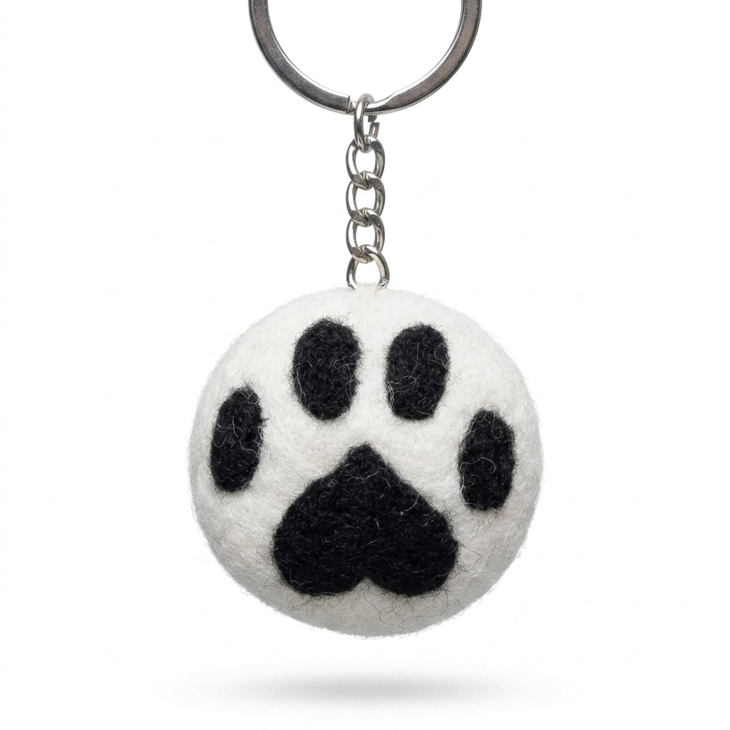 White wool felt cat paw keyring with black paw print on a white background