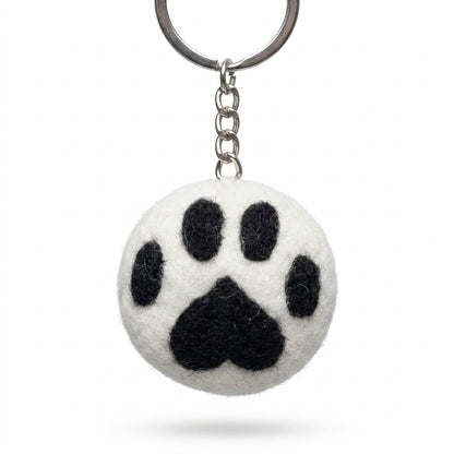 White wool felt cat paw keyring with black paw print on a white background
