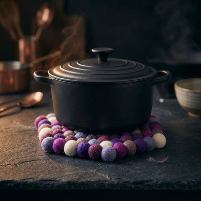 Black pot on a colorful felt trivet with a dark background