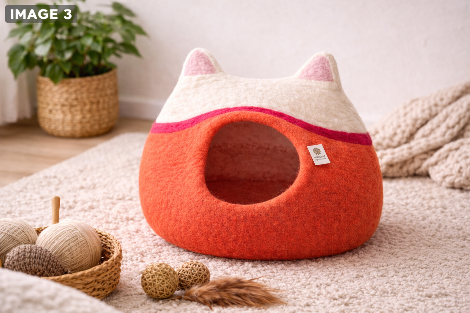 Orange pet bed with cat ears on a carpeted floor, surrounded by toys and a plant.