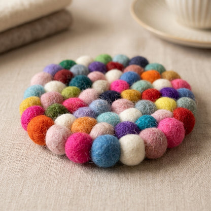 Confetti Mix multi wool felt coasters handmade in Nepal, colourful absorbent non-scratch drink coasters for wooden tables, host gifts, housewarming gifts and stocking fillers on a beige surface