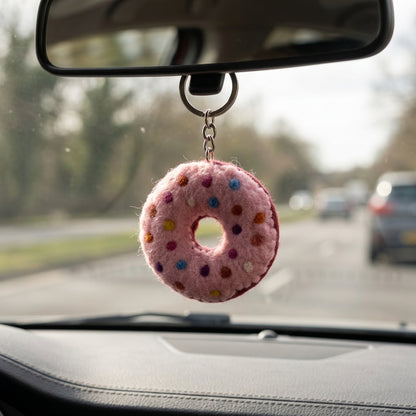  felt Pink donut keychain with colorful sprinkles on a car ornament hanging from a car's rearview mirror.