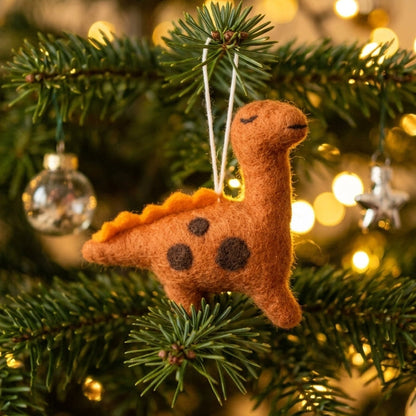 Felt dinosaur ornament hanging on a Christmas tree with blurred lights in the background