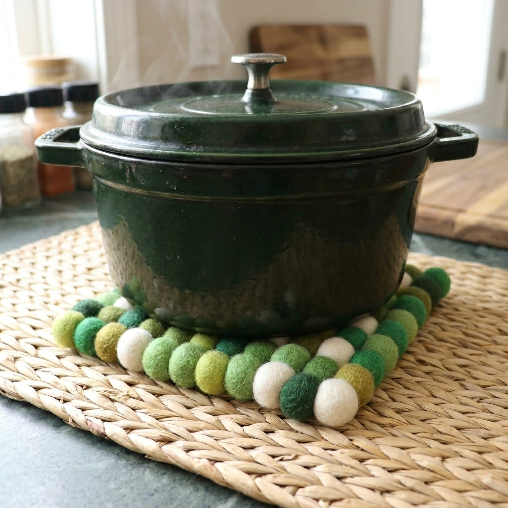 Green cast iron pot on a woven mat with a green felt trivet