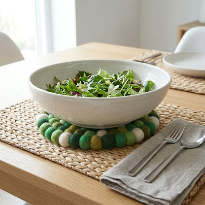 Bowl of salad on a woven placemat with cutlery and napkin on a wooden table.