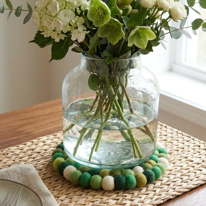 Bouquet of green and white flowers in a clear vase on a wooden table.