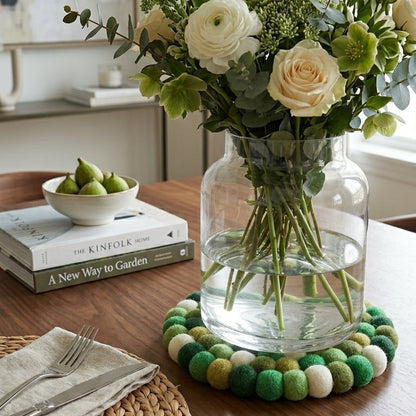 Bouquet of flowers in a vase on a table with books and a bowl of fruit.