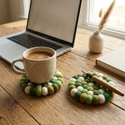 Mug on a Forest Mix Green wool felt coasters handmade in Nepal, botanical absorbent non-scratch drink coasters for wooden tables, plant lover gifts, host gifts and new home buyers with a laptop and notebook on a wooden desk.