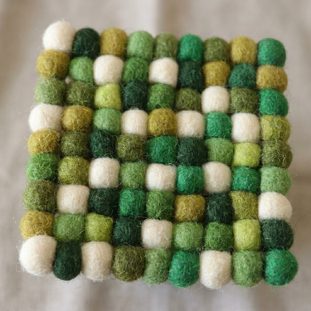 Square Forest Mix Green wool felt coasters handmade in Nepal, botanical absorbent non-scratch drink coasters for wooden tables, plant lover gifts, host gifts and new home buyers felt ball pattern on a plain background