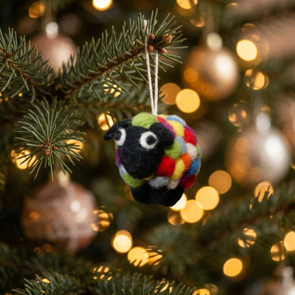 Colorful sheep ornament hanging on a Christmas tree with blurred lights in the background
