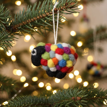 Colorful sheep ornament hanging on a Christmas tree with blurred lights in the background
