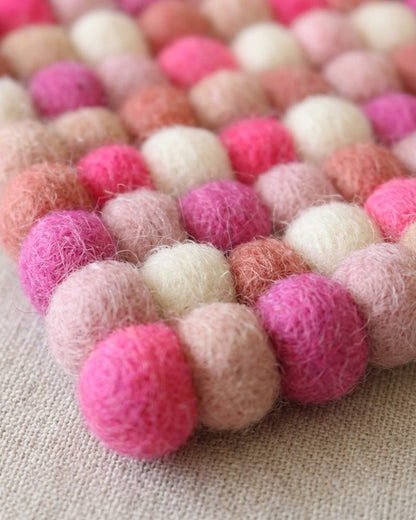 Pink and white felt ball rug on a light background