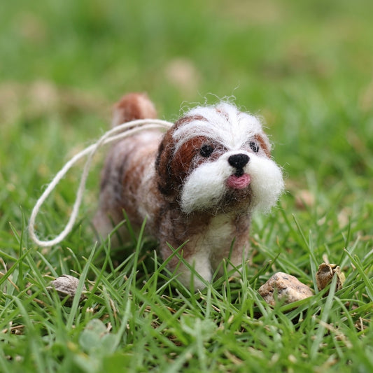 Handmade wool felt Shih Tzu dog ornament with hanging thread on a grassy field