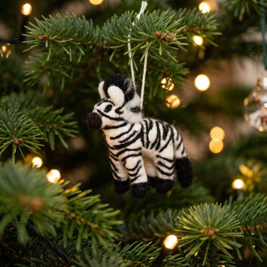 Handmade wool felt zebra ornament hanging on a Christmas tree with lights in the background