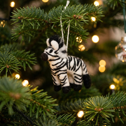 Handmade wool felt zebra ornament hanging on a Christmas tree with lights in the background